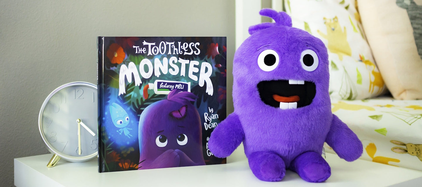 The Toothless Monster purple plush toy with hardcover Tooth Fairy book. Next to bed sitting on night stand.